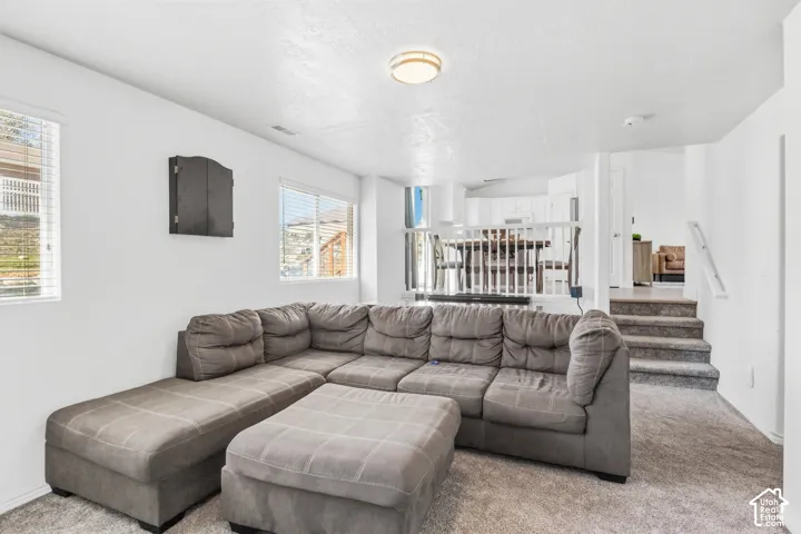 Wall-to-wall carpeting with multiple windows, recessed ceiling light, and a staircase with a white railing
