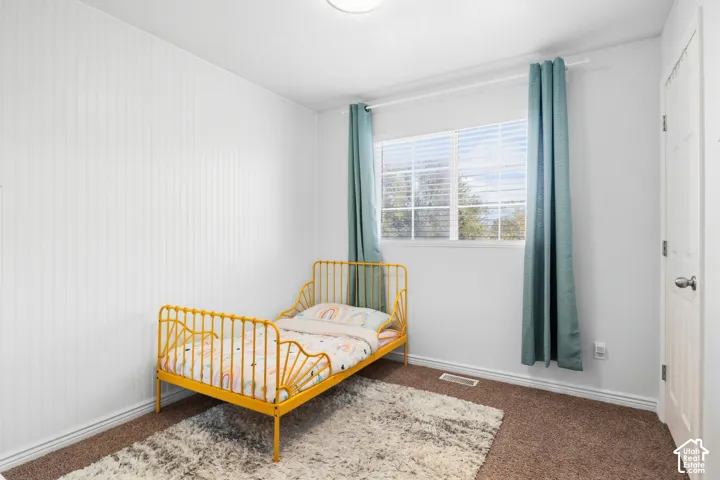 White vertical shiplap wall paneling, white window trim, white interior door, and neutral-tone carpet flooring