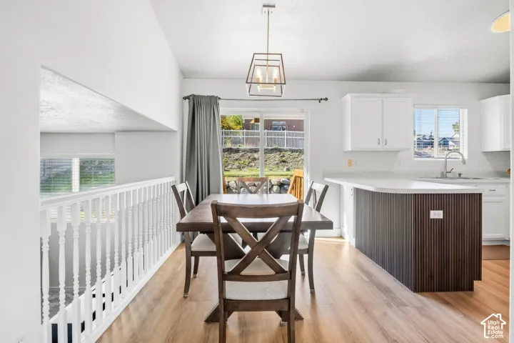 Open-concept dining area featuring wood-finish flooring, a contemporary pendant light fixture, and a white baluster railing