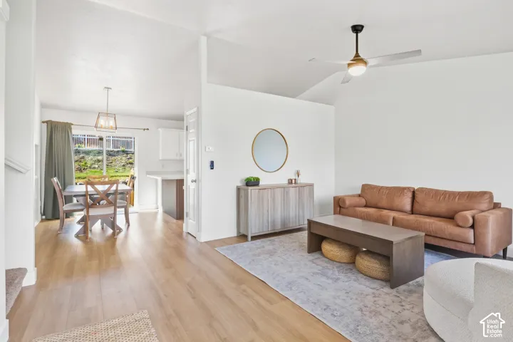 Vaulted ceilings, wood-finish flooring, modern ceiling fan, sliding glass door, and a built-in kitchen island