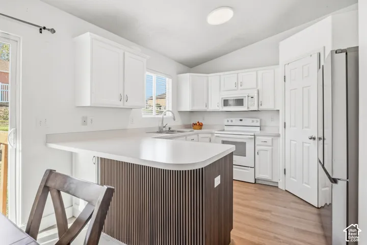 Kitchen featuring white cabinetry, light-toned countertops, a built-in microwave, and wood-finish flooring