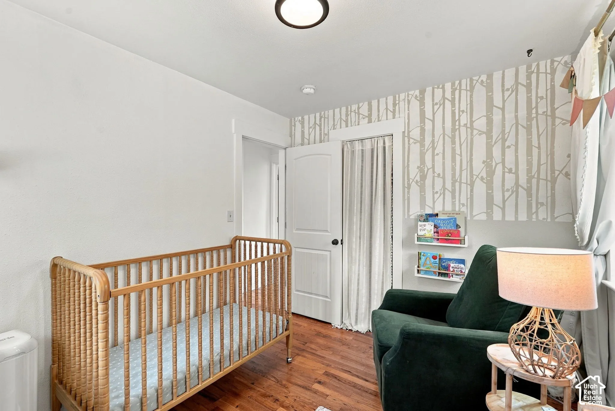 Hardwood flooring, painted walls, patterned accent wall, recessed lighting, and a solid door with black hardware