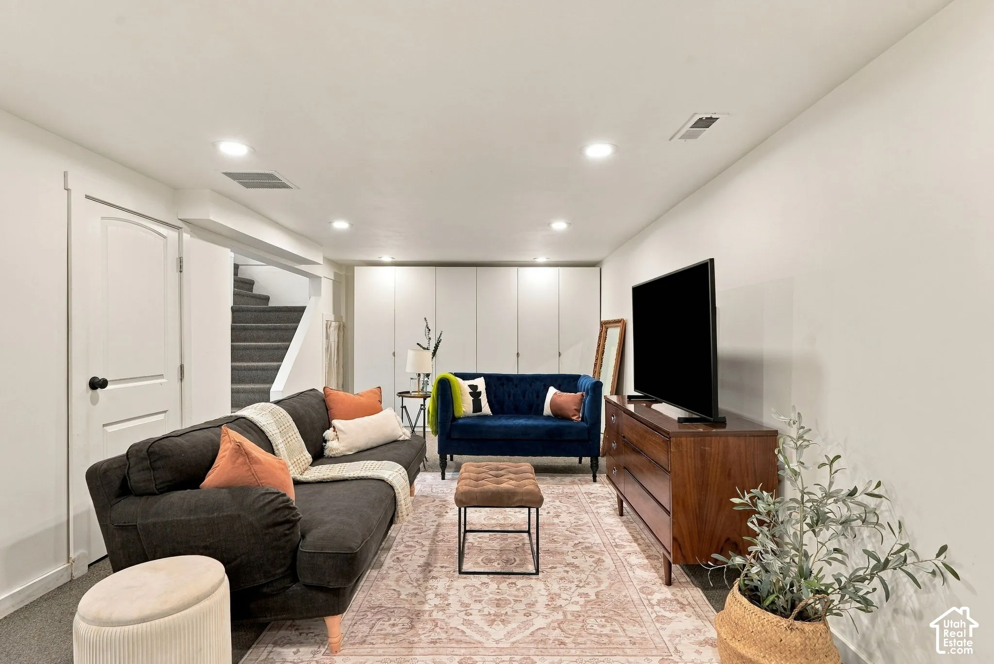 Recessed lighting, painted walls, built-in cabinetry, arched doorway, and carpeted stairs