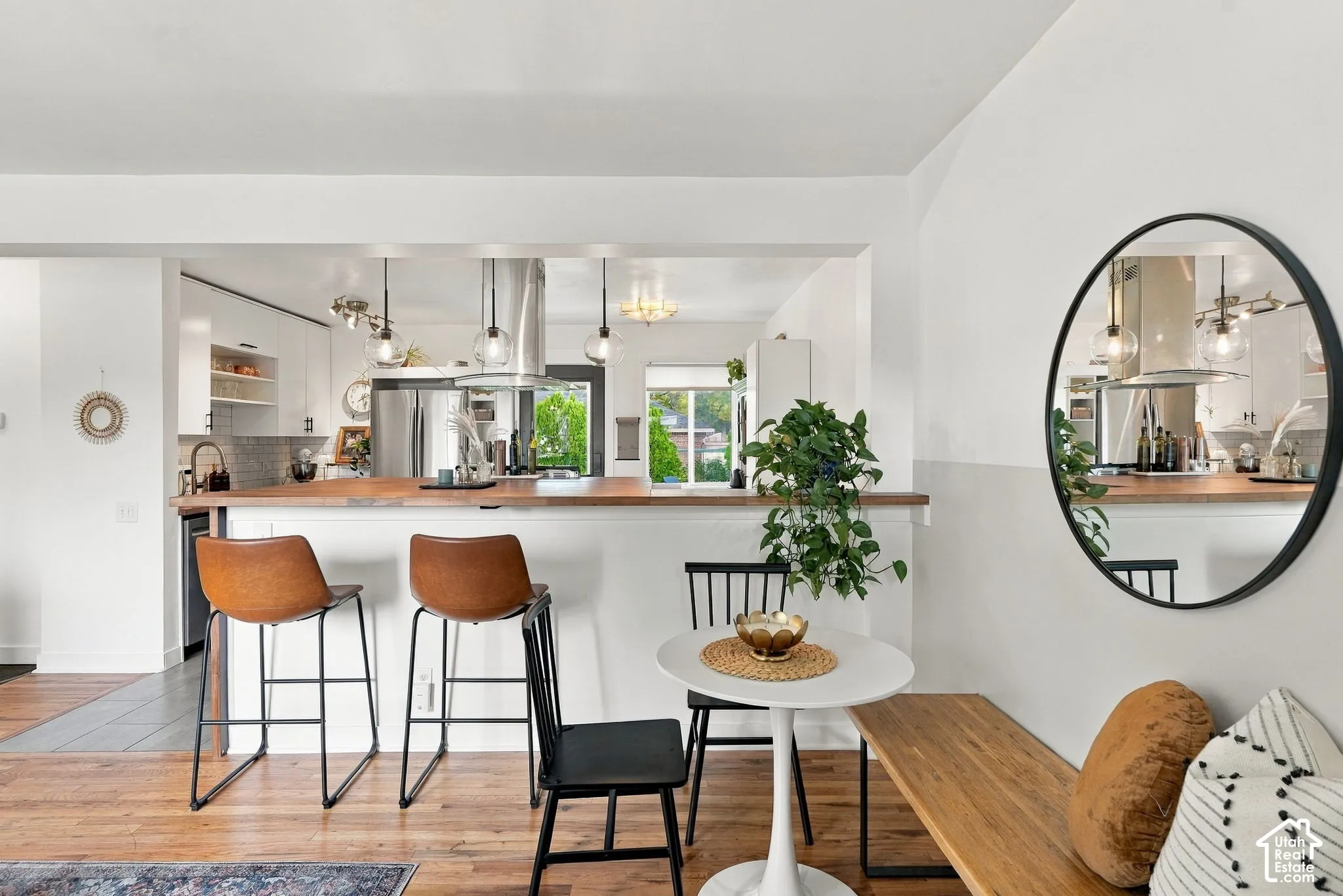Open-concept space featuring wood-finish flooring, a kitchen with a peninsula and wood-finish countertop, and stainless steel appliances