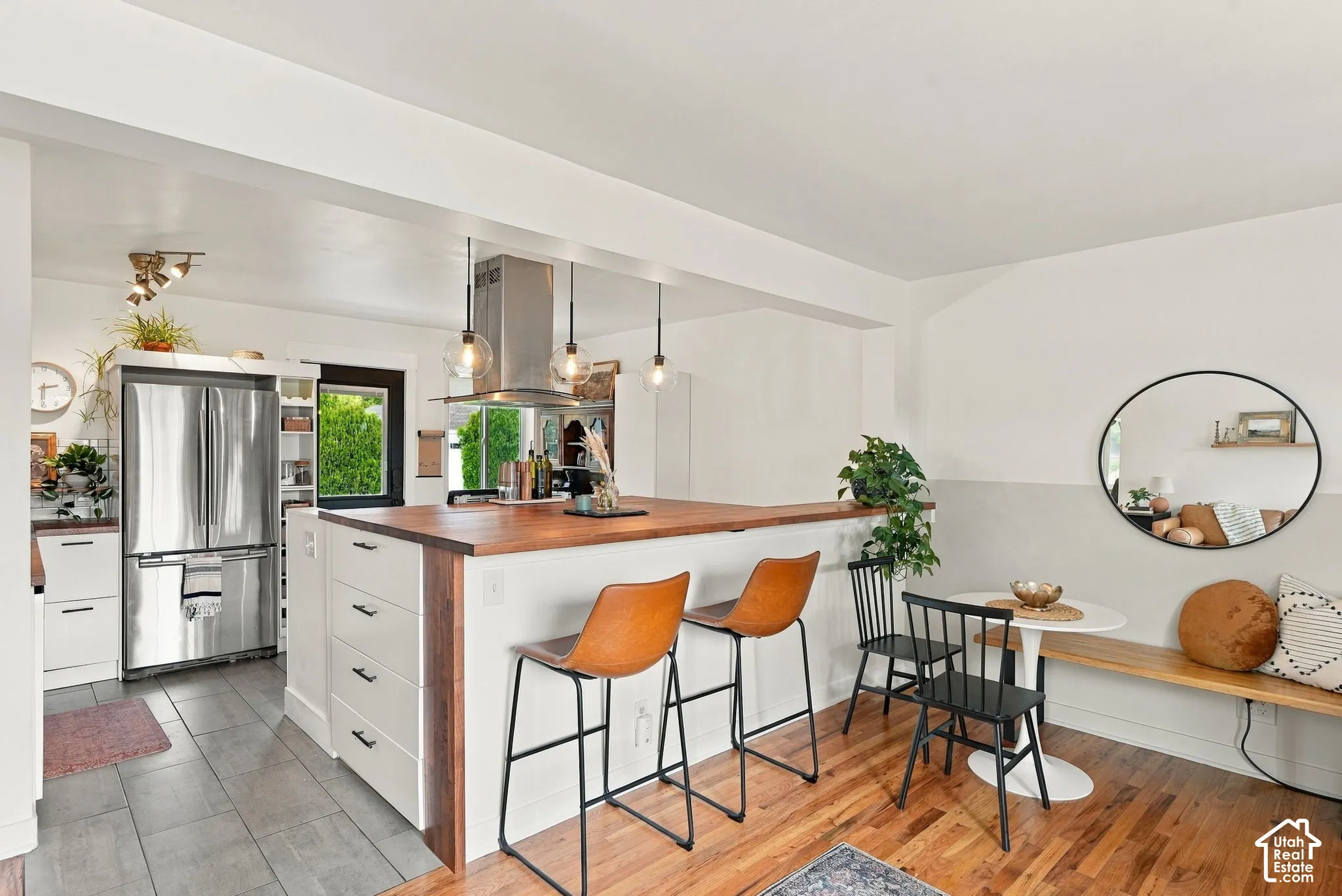 Open-concept kitchen and dining area featuring a wood-finish island with integrated storage, stainless steel appliances, and pendant lighting