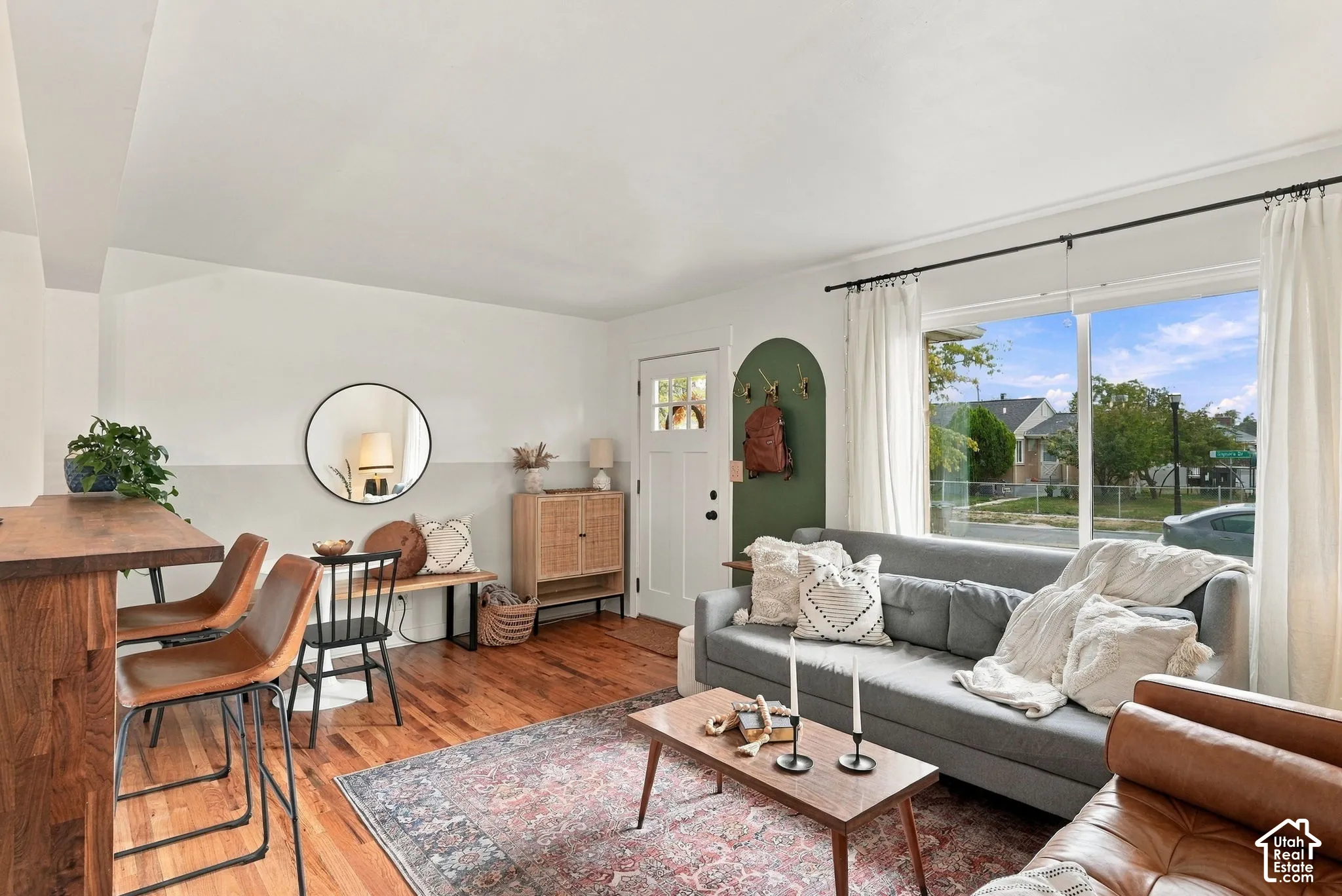 Hardwood flooring throughout, large picture window, white framed exterior door with glass panes, and a built-in archway feature
