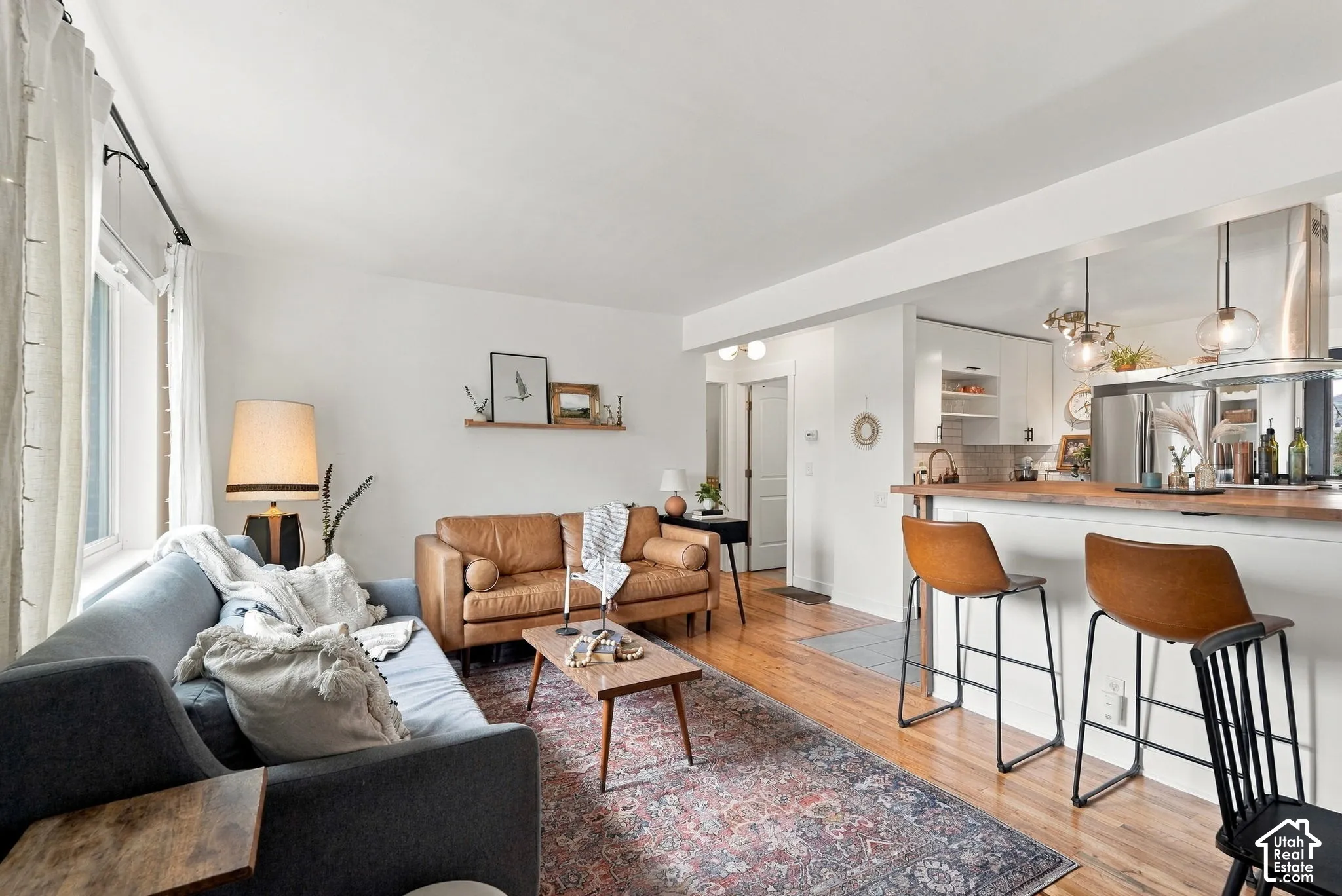 Open-concept living space featuring wood-finish flooring and a kitchen with an island, pendant lighting, and stainless steel appliances
