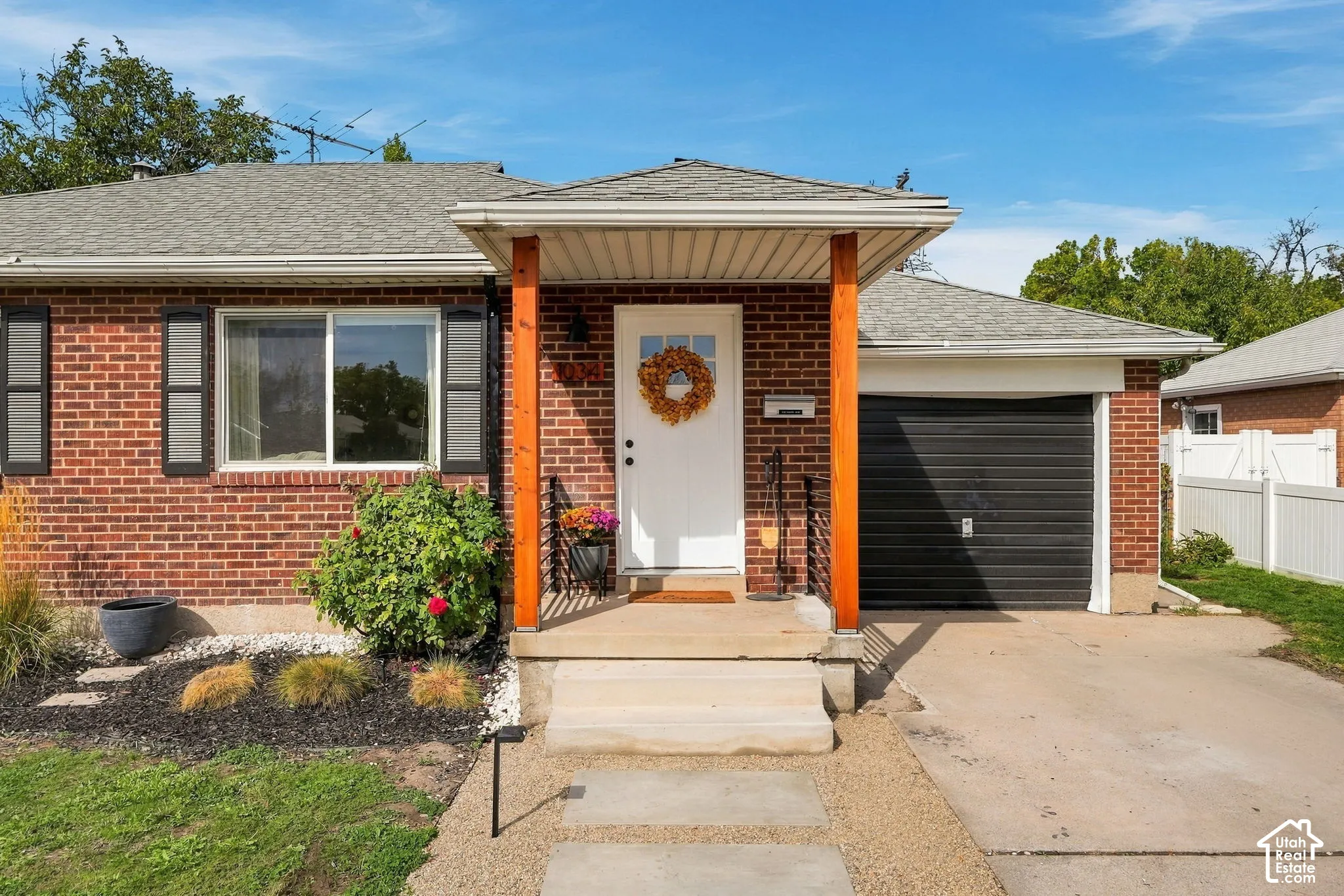 Brick exterior with a covered entry, black garage door, and a gray shingle roof