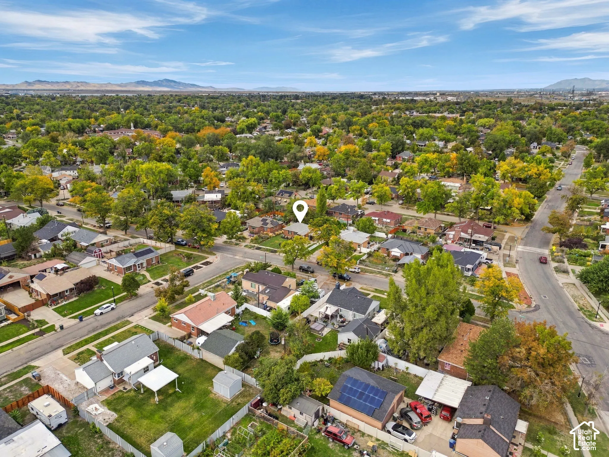 Aerial perspective of a neighborhood featuring mature trees, residential properties, and paved streets
