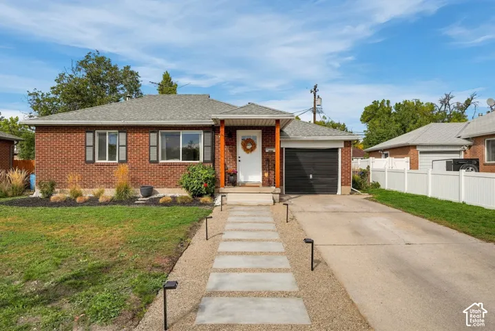Brick exterior with white trim, attached single-car garage, concrete driveway, and a gravel pathway with stepping stones