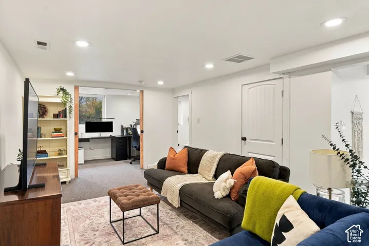 Recessed lighting illuminates a versatile living area with a built-in shelving unit, a desk area, and a solid panel interior door