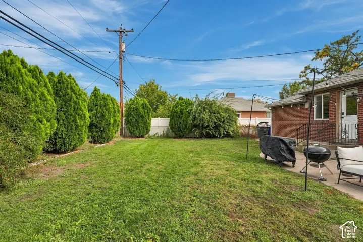 Expansive backyard with mature evergreen landscaping, manicured lawn, and brick exterior home