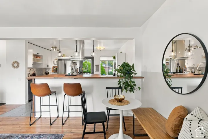 Open-concept space featuring wood-finish flooring, a kitchen with a peninsula and wood-finish countertop, and stainless steel appliances