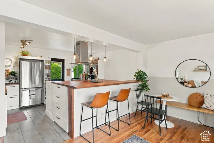 Open-concept kitchen and dining area featuring a wood-finish island with integrated storage, stainless steel appliances, and pendant lighting