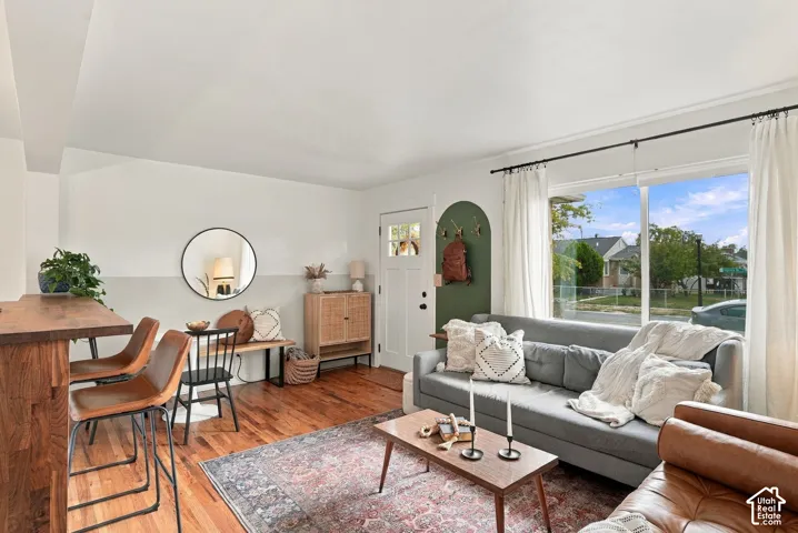 Hardwood flooring throughout, large picture window, white framed exterior door with glass panes, and a built-in archway feature