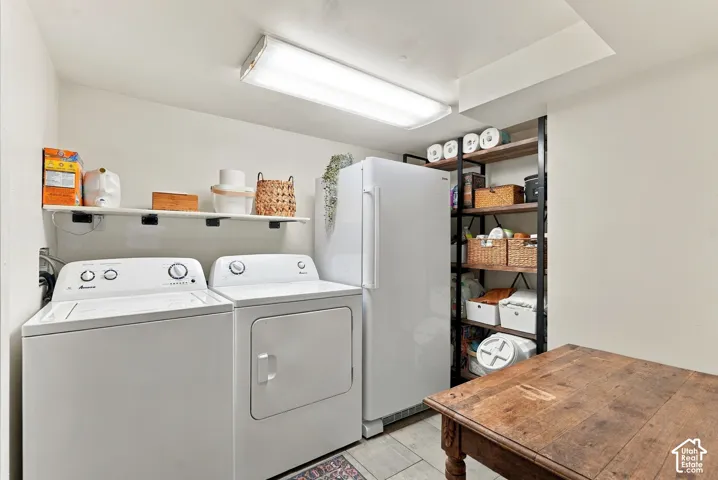 Laundry area featuring a top-load washer, front-load dryer, wall-mounted shelving, and adjacent open shelving with wood-finish shelves