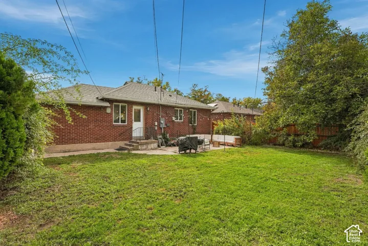 Expansive backyard featuring a manicured lawn, red brick exterior, and a concrete patio