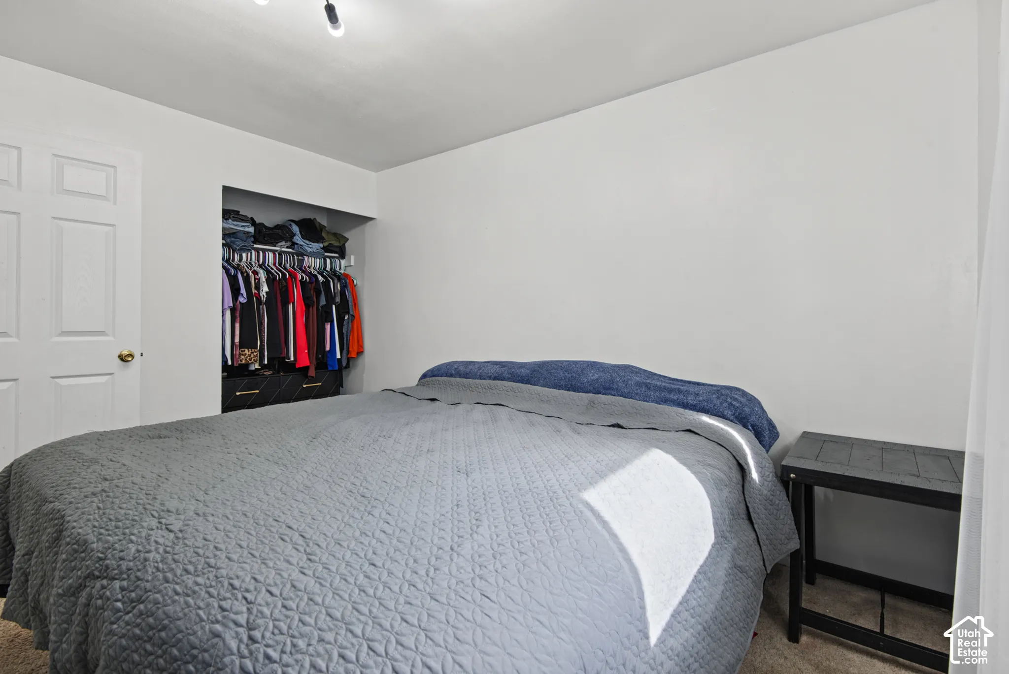 Built-in closet with hanging rod white interior walls, and wall-mounted track lighting