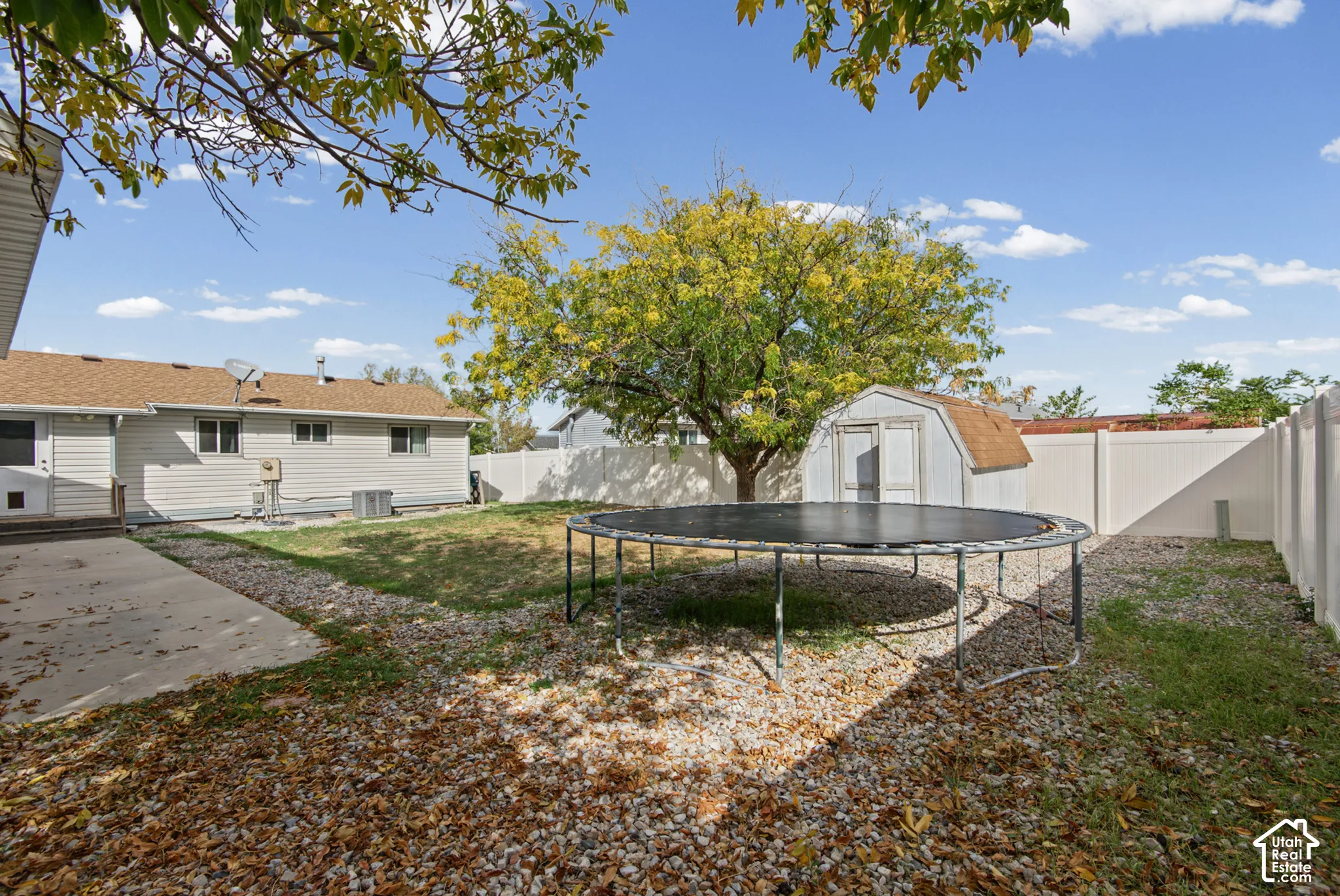 Expansive backyard featuring a concrete patio, a storage shed, and a privacy fence