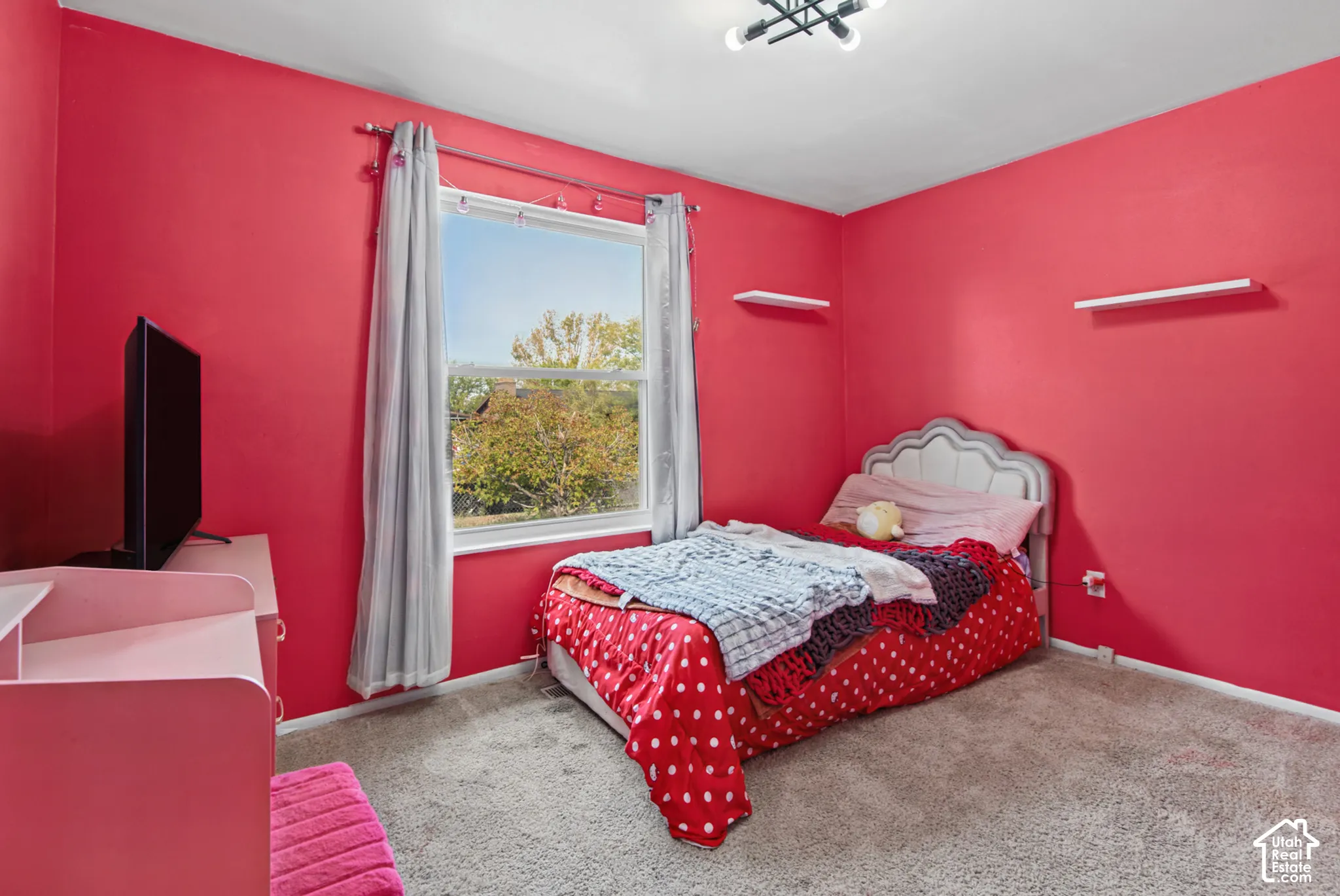 Wall-to-wall carpeting and a double-pane window with curtain rods
