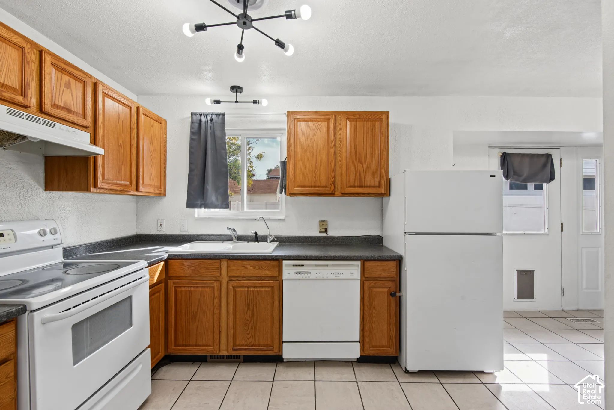 Kitchen featuring wood-finish cabinetry, white appliances, and tiled flooring