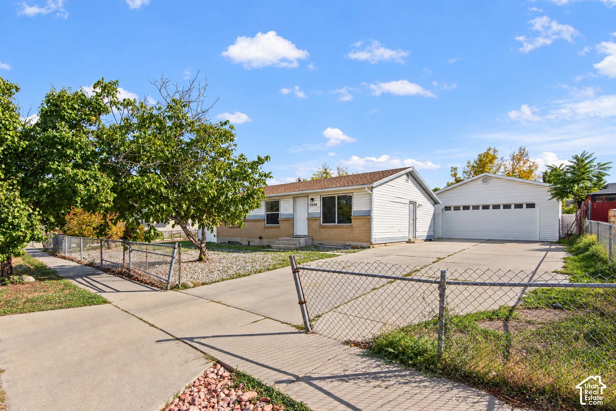 Single-story residence with brick and siding exterior, concrete driveway, and an additional detached garage structure