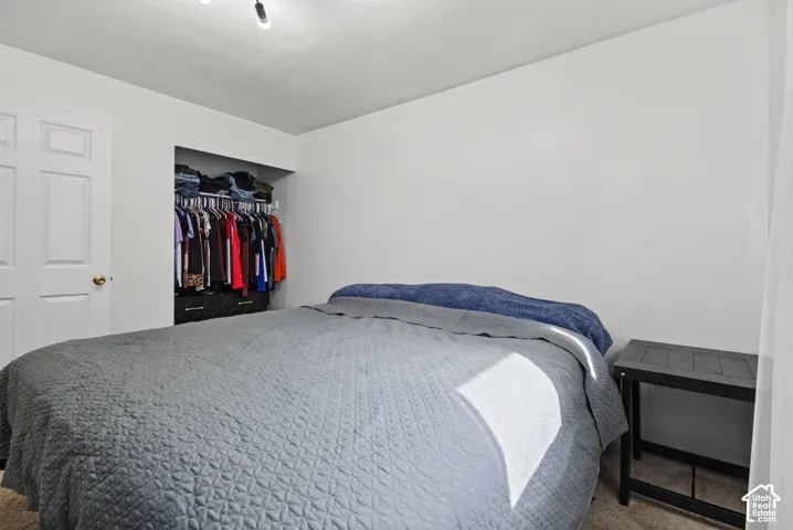 Built-in closet with hanging rod white interior walls, and wall-mounted track lighting
