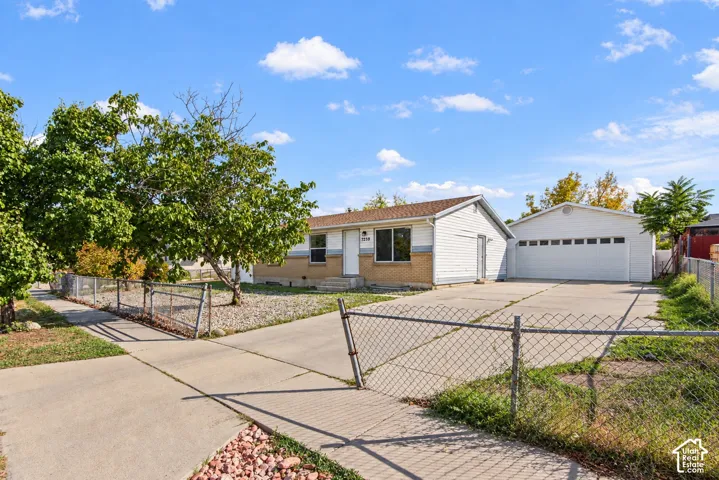 Single-story residence with brick and siding exterior, concrete driveway, and an additional detached garage structure