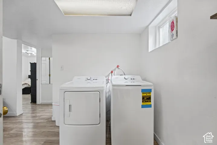 Laundry area featuring a window, wood-finish flooring, and white walls