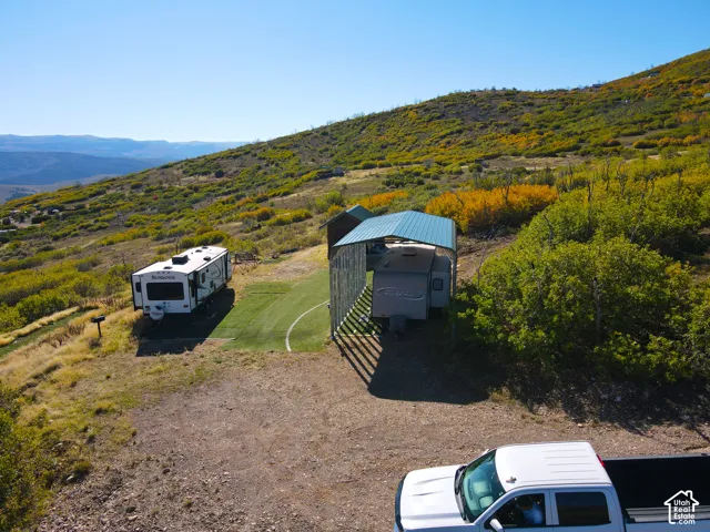 RV parking with a covered structure, gravel driveway, and surrounding natural landscaping