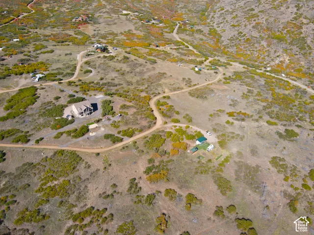 Expansive property featuring a multi-level residence, natural foliage, and winding dirt roads