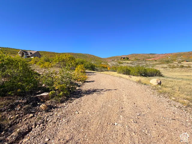 Expansive landscape featuring a gravel path and distant residence nestled into the hillside