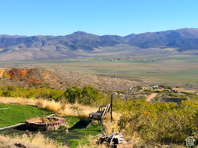 Brick fire pit with artificial turf, surrounded by natural landscaping and distant mountains