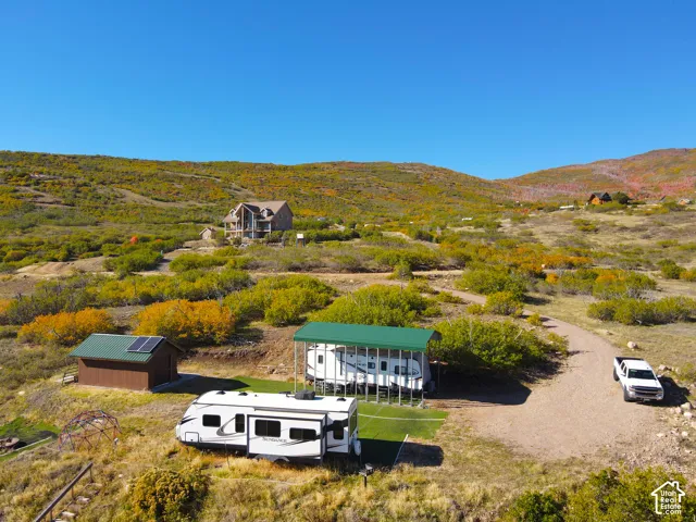 Expansive property featuring a gravel driveway, a detached shed with solar panels, and a covered RV parking structure