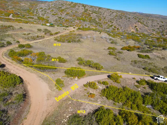 Expansive natural terrain featuring an unpaved access road, scattered natural vegetation, and a mountainous backdrop