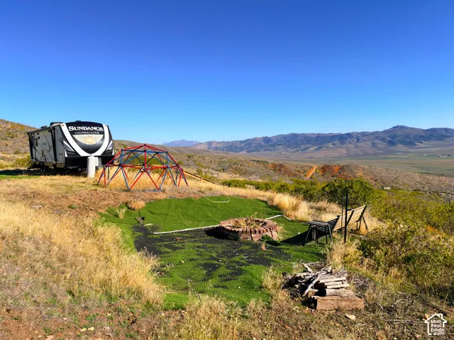 Expansive outdoor area featuring a built-in fire pit, artificial turf, and a geometric play structure
