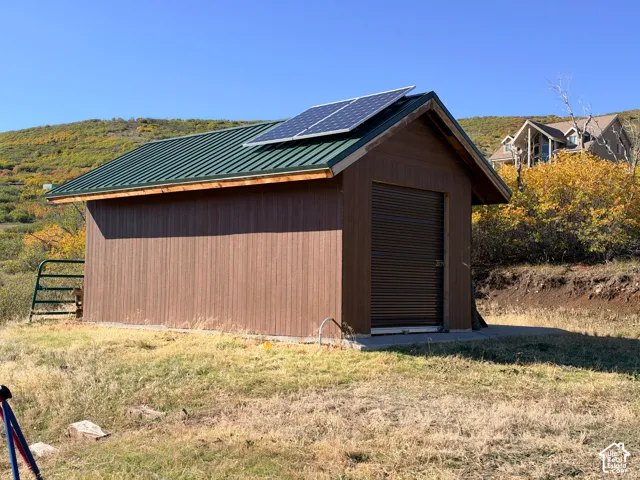 Detached structure featuring a metal roof, solar panels, and a roll-up door
