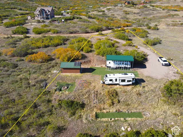 Gravel driveway access, a brown outbuilding with solar panels, and a covered RV pad with artificial turf