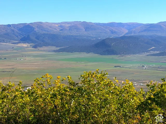 Expansive natural landscape with distant mountain ranges and a verdant valley floor