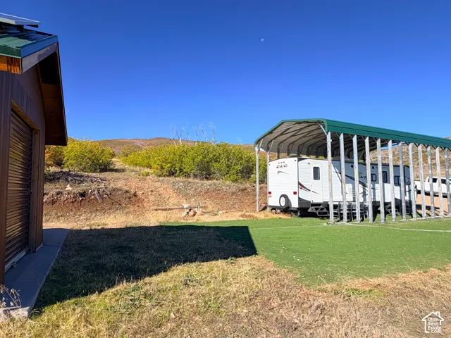 Metal-sided storage building with a green roof, dedicated RV parking structure, and an artificial turf area