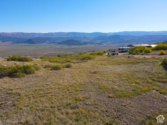 Expansive open land featuring distant mountainous scenery and natural ground cover