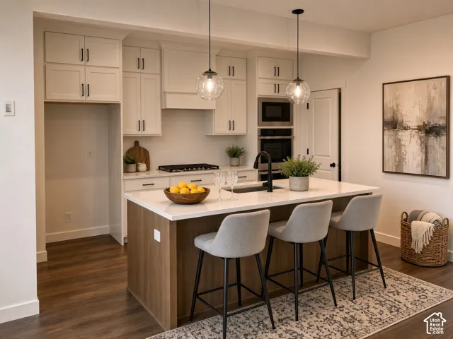Kitchen featuring white shaker cabinetry, wood-finish flooring, a central island with a white countertop, subway tile backsplash, and stainless steel built-in appliances