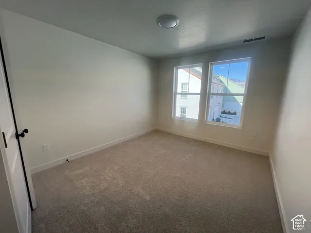 Carpeted room featuring two windows, recessed ceiling lighting, and a white interior door with matte black hardware