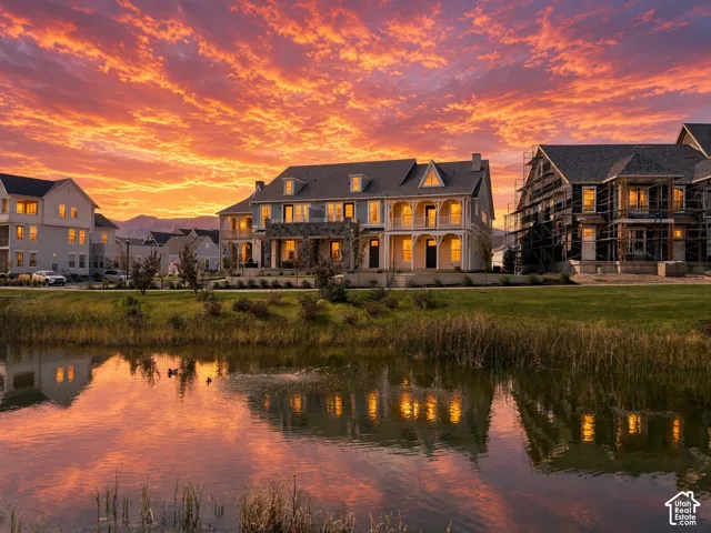 Waterfront property featuring a pond, established landscaping, and mountain scenery