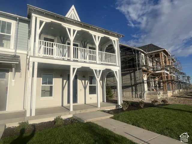 Two-story exterior with a covered porch, upper-level balcony, decorative balusters, and a gabled dormer