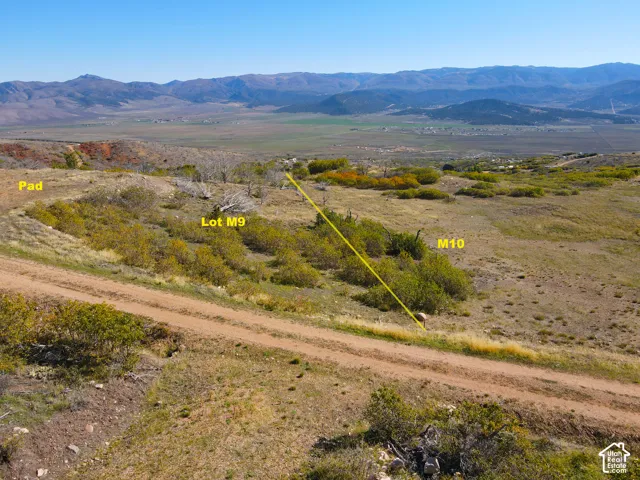 Mountain landscape, expansive acreage, natural terrain, scattered vegetation, clear blue sky