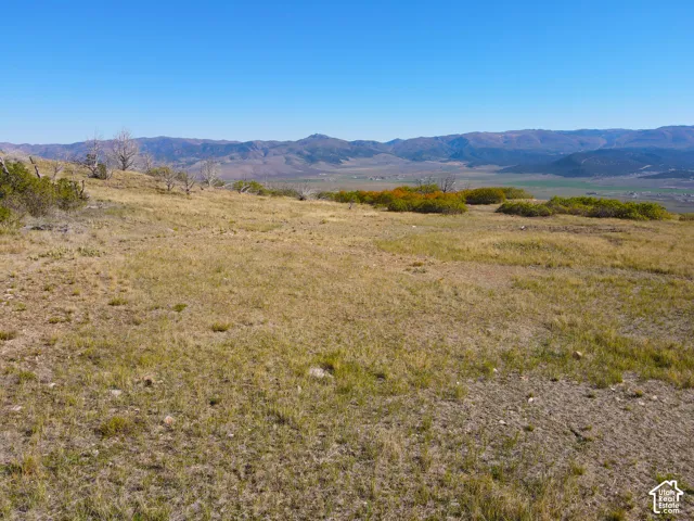 Expansive open terrain with natural ground cover, distant mountain ranges, and a clear sky