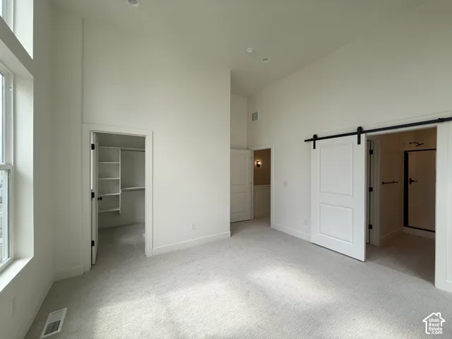 High ceilings with recessed lighting, integrated shelving in a walk-in closet, and a sliding barn door