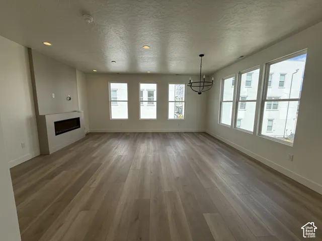 Recessed lighting, wood-finish flooring, linear fireplace, multiple windows, and a black chandelier