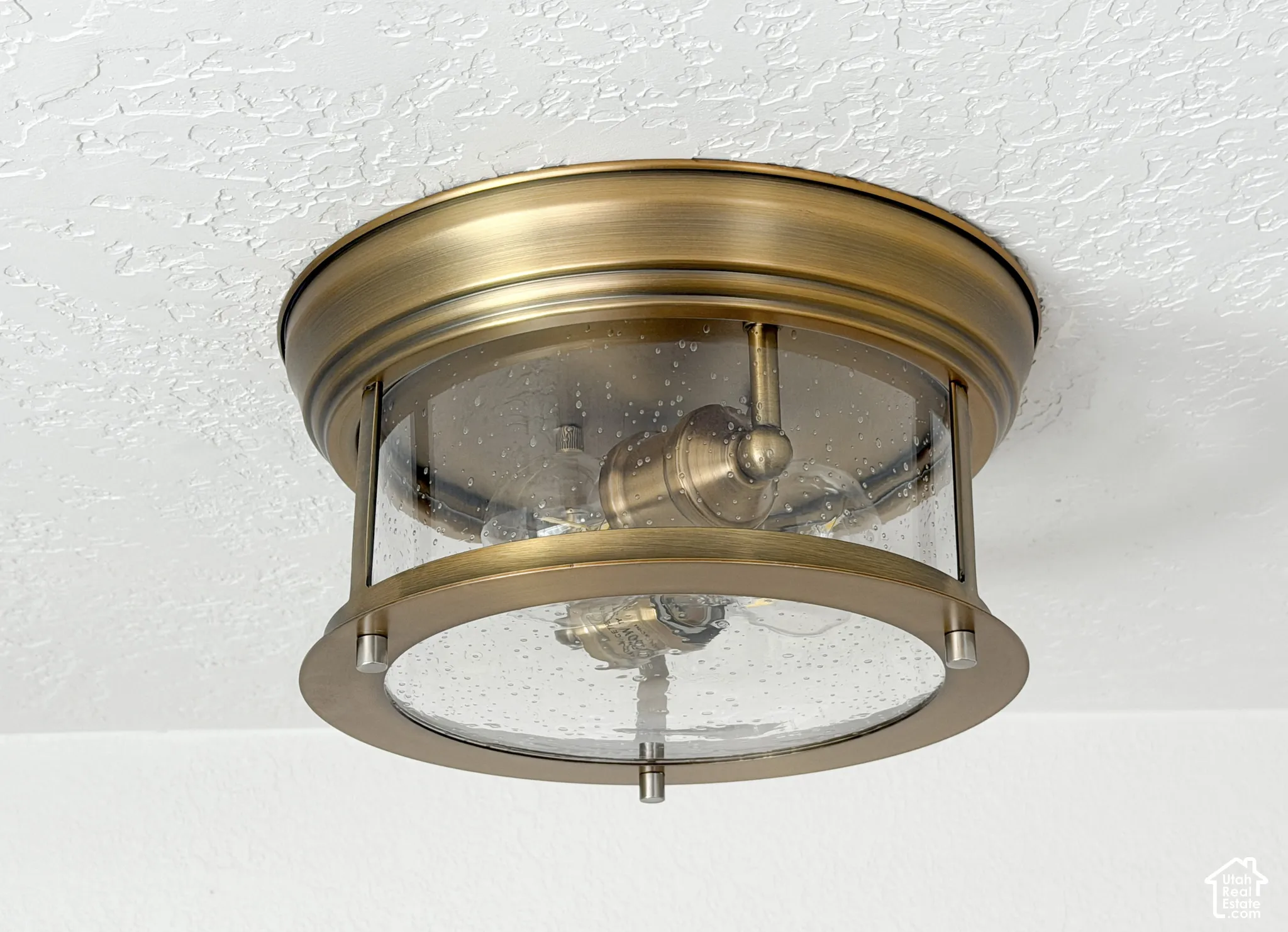 Ceiling-mounted fixture featuring an antique brass finish and clear seeded glass